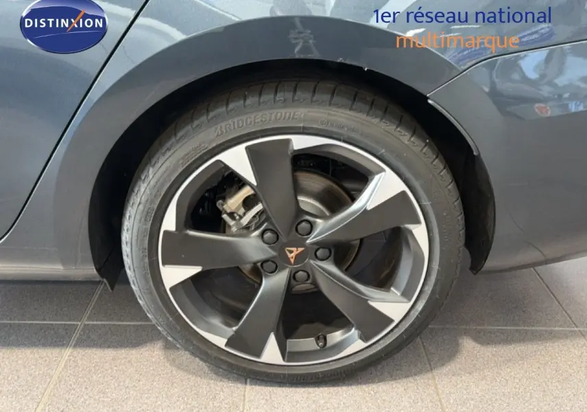 Gros plan sur la roue arrière droite d'une CUPRA LEON ST gris magnétique métal avec jante bi-ton et logo CUPRA central.