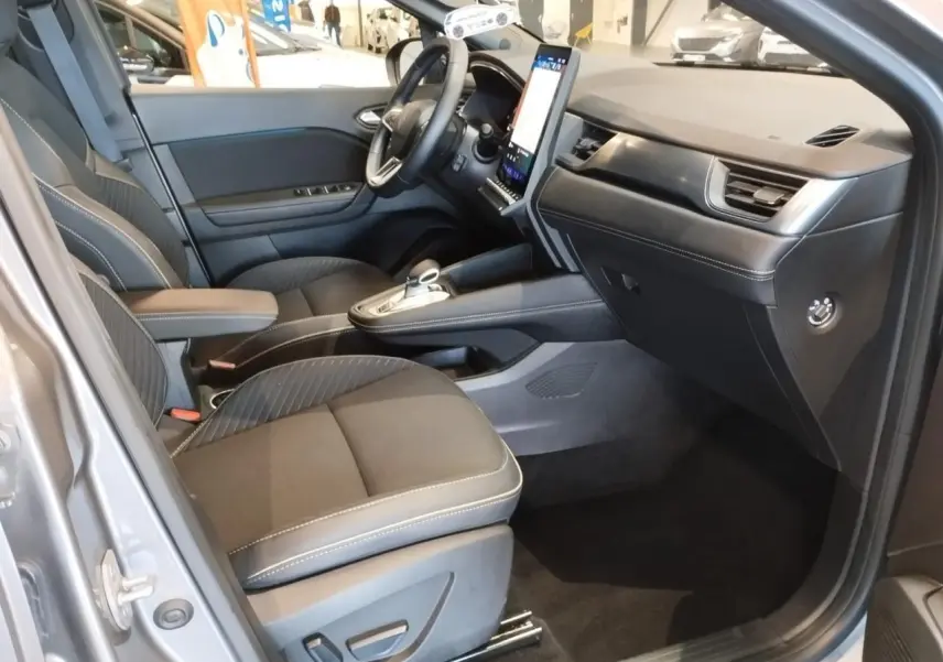 Vue intérieure côté conducteur du Renault SYMBIOZ gris Cassiopée, avec sièges noirs et écran tactile vertical.