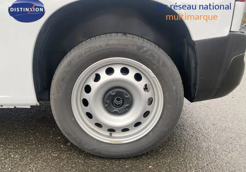 Gros plan sur la roue avant droite en jante acier du Citroën Berlingo Fourgon blanc, avec partie basse de la carrosserie visible.