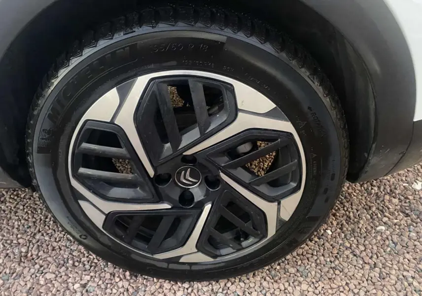 Gros plan sur la roue avant droite d'une Citroën C4 blanche de 2021, avec jante alliage au design moderne.