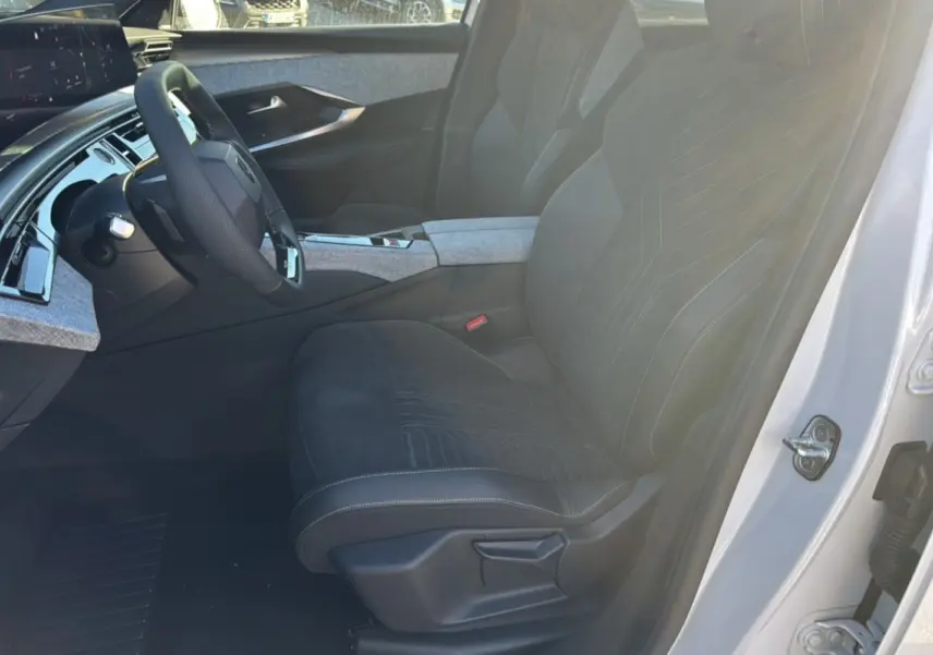 Vue intérieure côté conducteur du Peugeot 3008 Hybrid 136 GT Plus 2024 blanc okénite, sièges noirs avec surpiqûres et tableau de bord moderne.