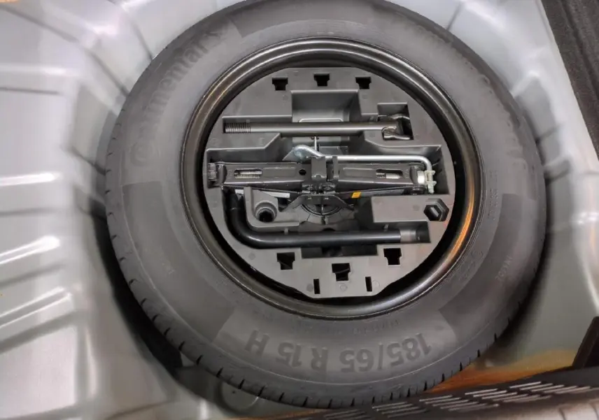 Gros plan sur la roue de secours tôle noire et ses outils dans le coffre d'une Renault Clio gris foncé 2024.