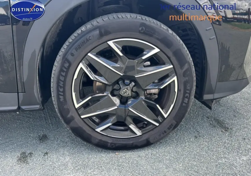 Gros plan sur la roue avant droite noire du Peugeot 5008 Hybrid 145 allure e-dcs6 avec jante alu distinctive.