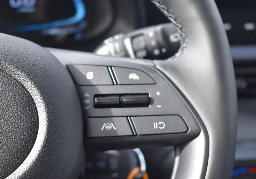 Gros plan sur les commandes multifonctions du volant en cuir noir de la Hyundai i20 1.2 79 Intuitive 2025.