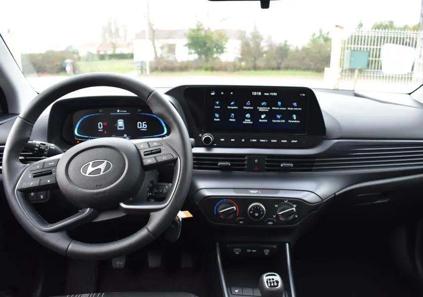 Vue intérieure avant du tableau de bord et volant cuir noir de la Hyundai i20 2025 avec écran tactile central.