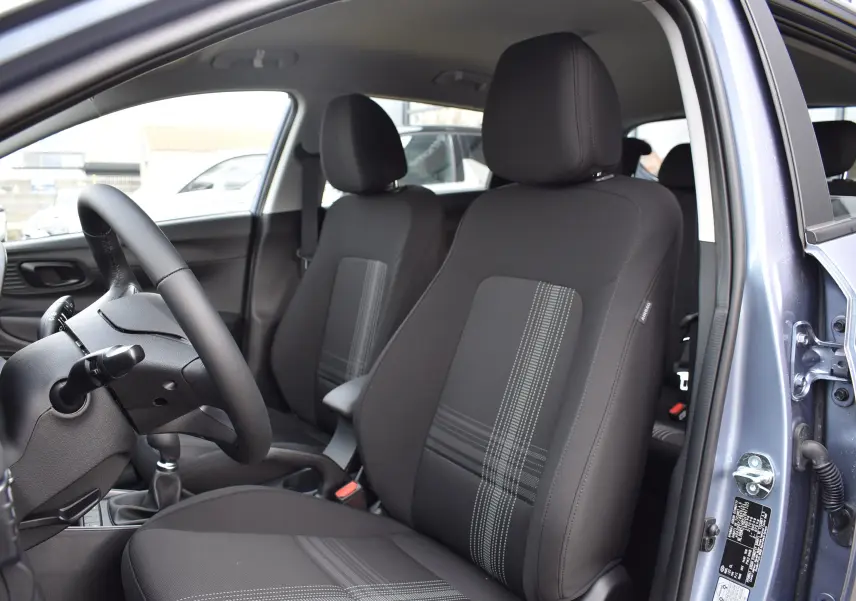 Vue intérieure côté conducteur de la Hyundai i20 2025 bleu clair, sièges tissu noir avec motifs gris et volant cuir.