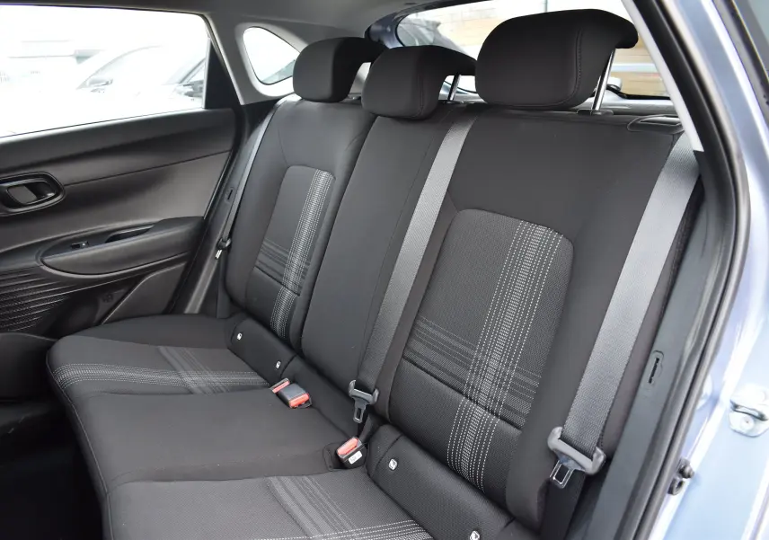 Vue intérieure côté droit montrant la banquette arrière noire avec motifs gris d'une Hyundai i20 bleu clair 2025.