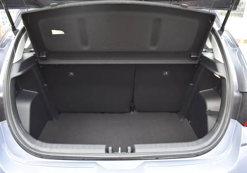 Coffre ouvert d'une Hyundai i20 bleu clair vue arrière, avec cache-bagages rigide et intérieur noir.