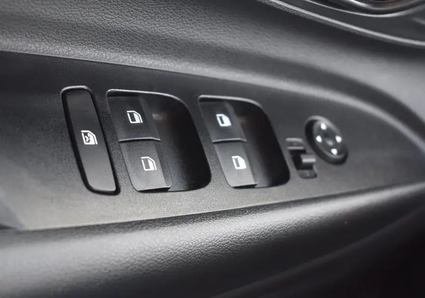 Gros plan sur les commandes de lève-vitres et réglage des rétroviseurs côté conducteur d’une Hyundai i20 2025.