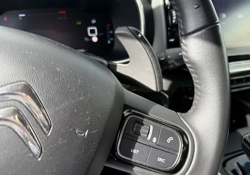 Gros plan sur le volant en cuir noir du Citroën C5 Aircross 2021 avec commandes audio et palettes au volant.