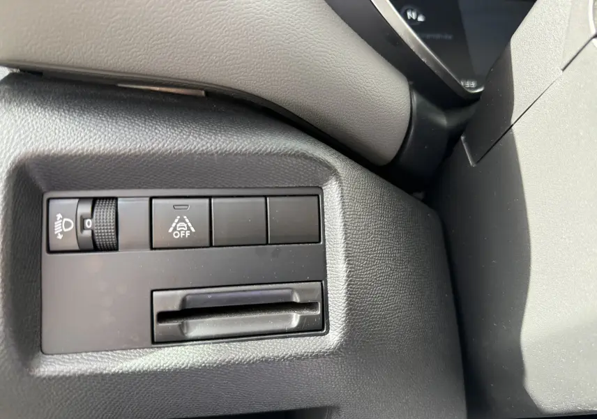 Gros plan sur les commandes de réglage des phares et d'assistance à la conduite dans l'habitacle noir du Citroën C5 Aircross.