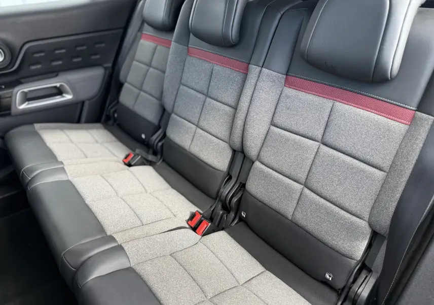 Vue intérieure des sièges arrière du Citroën C5 Aircross 2021, tissu gris avec bande rouge et garnitures noires.