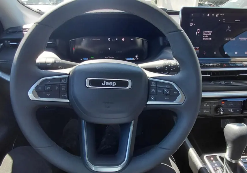Vue intérieure centrée sur le volant Jeep noir et l’écran tactile du tableau de bord du Compass 2025.