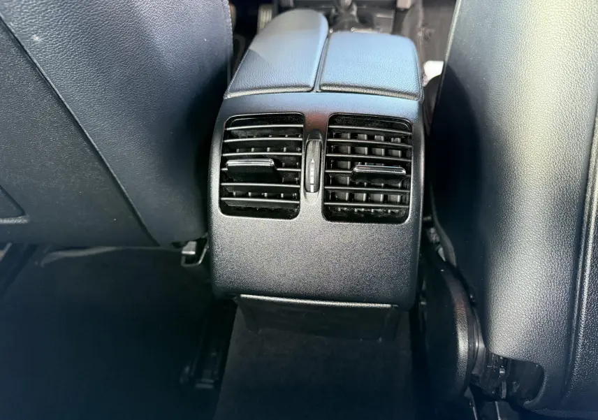 Gros plan sur les aérateurs arrière noirs entre les sièges avant d'une Mercedes Classe E 250 Coupé gris.