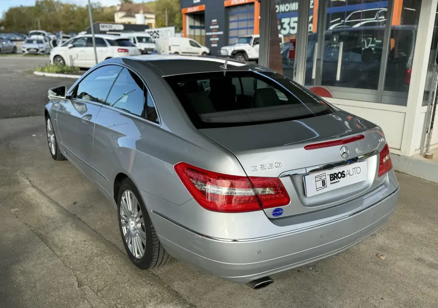 Mercedes Classe E 250 Coupé gris vu en 3/4 arrière droit, avec feux arrière rouges et jantes alliage.
