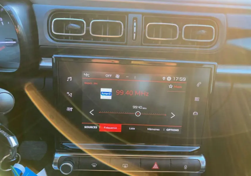 Écran tactile multimédia allumé sur la radio, tableau de bord intérieur de Citroën C3 Shine 2023, ambiance sombre.