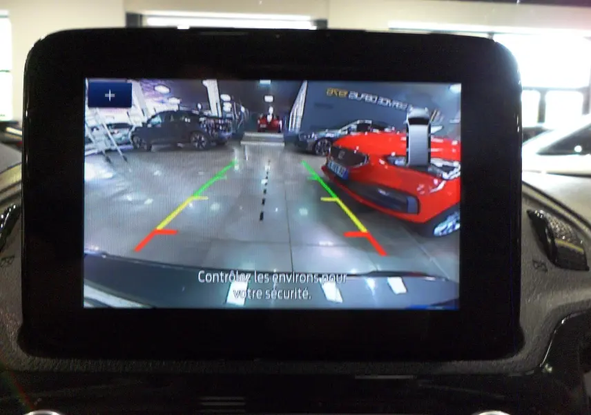 Vue de l'écran de caméra de recul du Ford Grand Tourneo Connect 2020, montrant un parking intérieur avec une voiture rouge à droite.