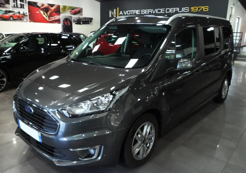 Vue 3/4 avant d'un Ford Grand Tourneo Connect gris Magnetic 2020 en showroom avec jantes alliage et vitres teintées.