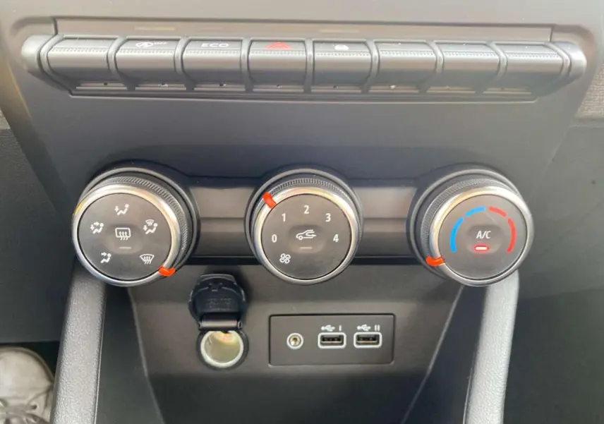 Gros plan sur les commandes de climatisation manuelle et les ports USB de la Renault Clio Evolution 2025 en noir étoilé.