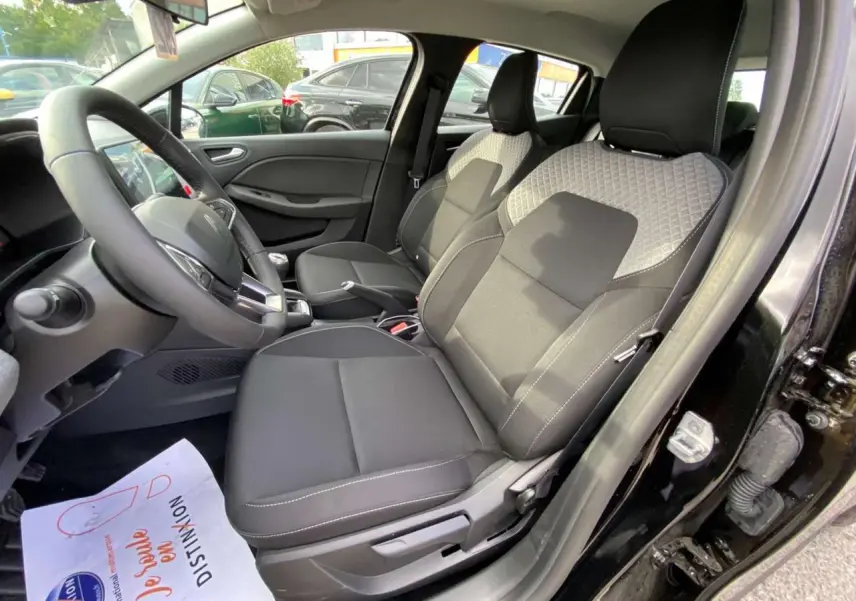 Vue intérieure côté conducteur de la Renault Clio 2025 noir étoilé avec sièges tissu bicolore et volant multifonction.