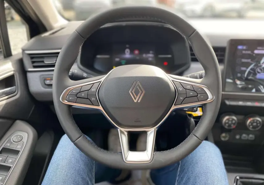 Vue rapprochée du volant Renault Clio 2025, avec commandes intégrées et tableau de bord numérique en arrière-plan.