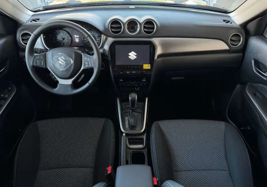 Intérieur du Suzuki Vitara 2025 en vue frontale, tableau de bord noir avec écran central tactile et volant multifonction.