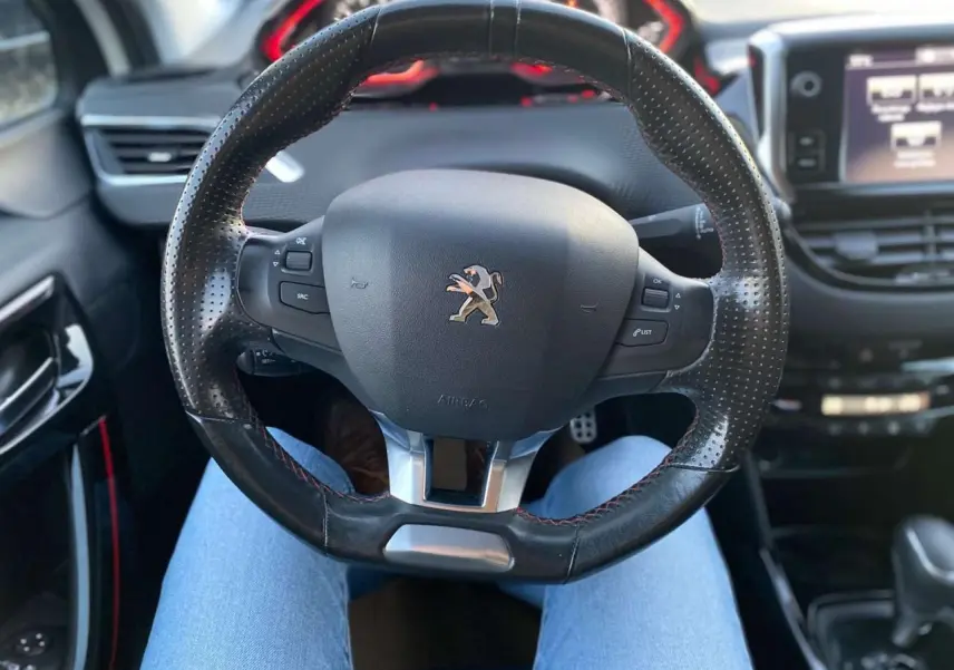 Vue rapprochée du volant en cuir perforé du Peugeot 2008 blanc 2016 GT Line avec commandes intégrées.