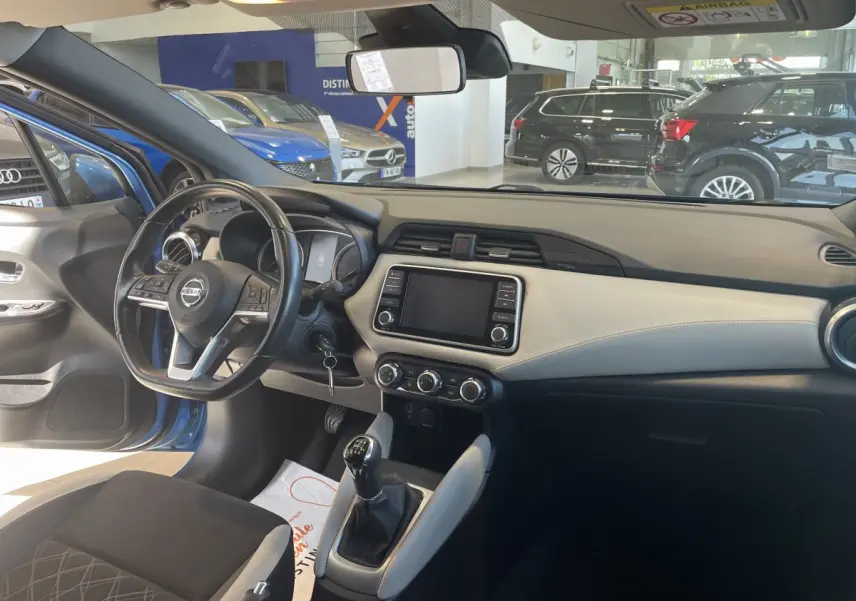 Intérieur avant droit d'une Nissan Micra bleu 2020, volant cuir multifonctions et écran tactile central visible.