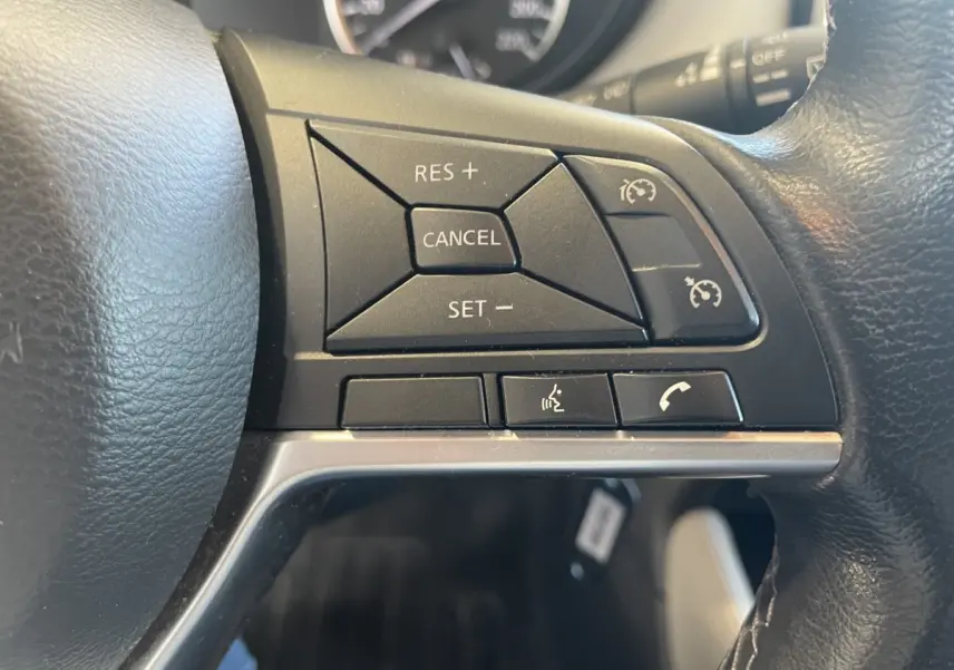 Gros plan sur les commandes de régulateur de vitesse et téléphone au volant cuir noir de la Nissan Micra bleu 2020.