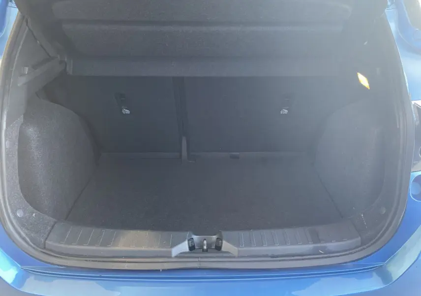 Coffre ouvert vu de l'arrière d'une Nissan Micra IG-T 100 N-Connecta bleu, espace de chargement vide et éclairage intérieur allumé.