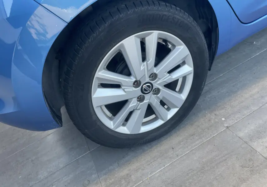 Gros plan sur la roue avant gauche d'une Nissan Micra bleu 2020, avec jante alliage et pneu Bridgestone.