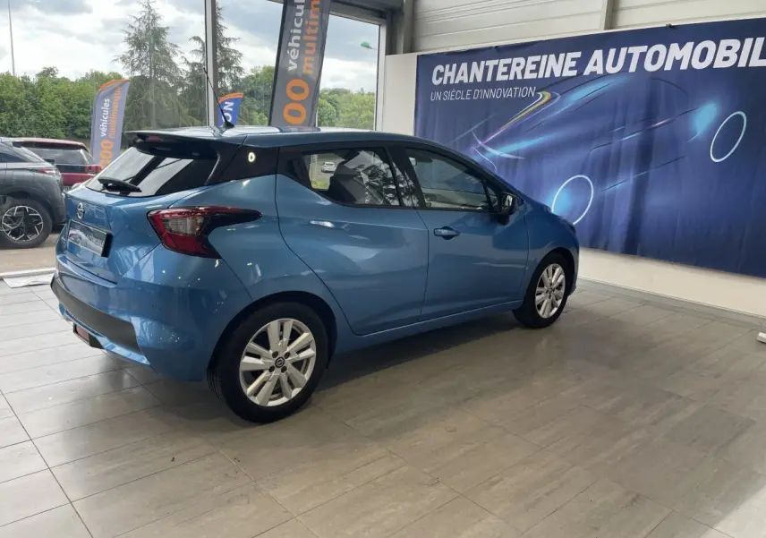 Nissan Micra IG-T 100 N-Connecta bleu vue 3/4 arrière droit en intérieur, avec jantes alliage et vitres teintées.