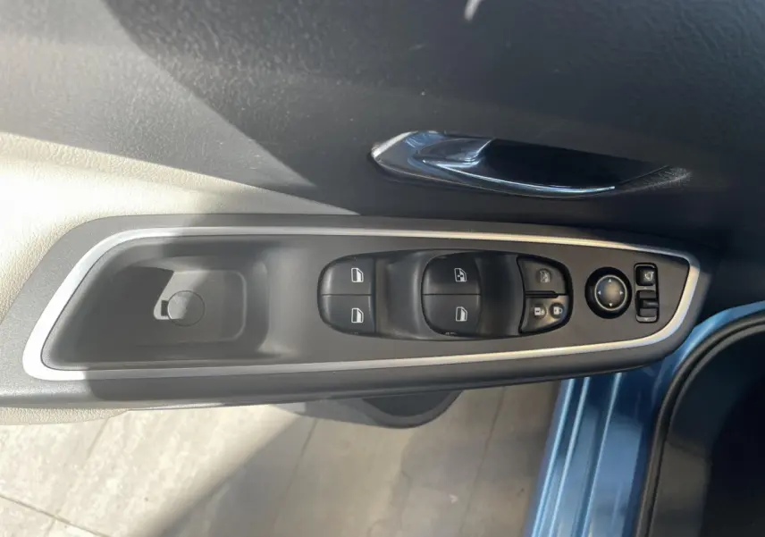 Vue rapprochée du panneau de commandes des vitres et rétroviseurs côté conducteur d'une Nissan Micra bleu 2020.