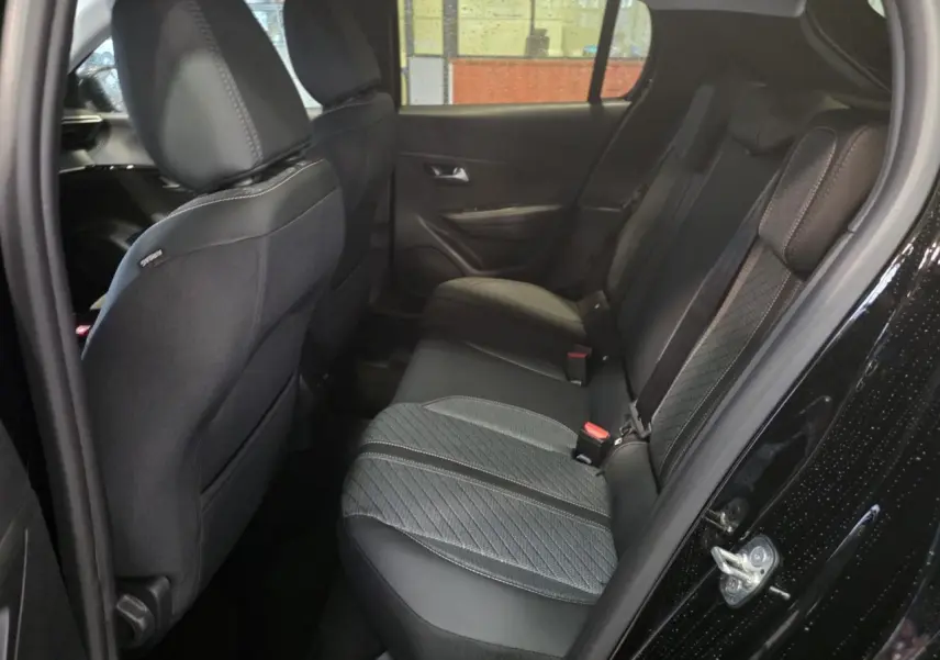 Vue intérieure arrière droite de la Peugeot 208 noire métallisée, montrant la banquette tissu bi-matière avec surpiqûres Quartz.