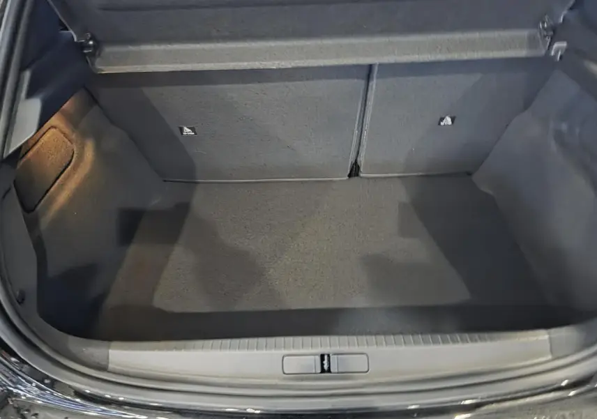 Coffre ouvert de la Peugeot 208 noire métallisée, montrant un espace de rangement propre et vide.