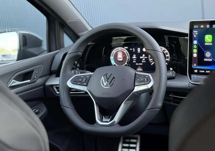 Vue intérieure centrée sur le volant sport Volkswagen Golf VIII avec tableau de bord numérique et écran tactile.