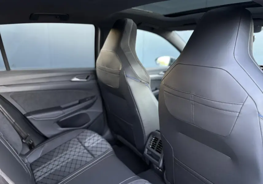 Vue intérieure arrière droite de la Volkswagen Golf VIII R-Line 2026, sièges sport en cuir noir avec surpiqûres bleues.