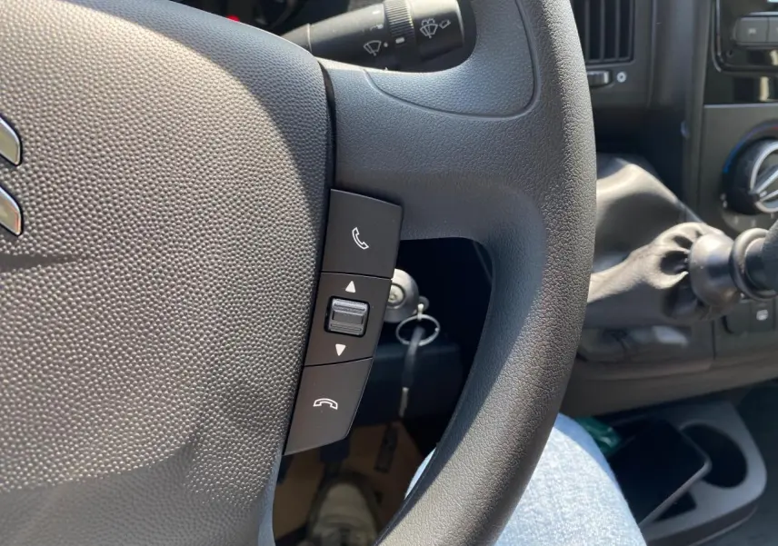 Gros plan sur le volant noir du Citroën Jumper 2023 avec commandes d'appel intégrées et levier de vitesses visible.