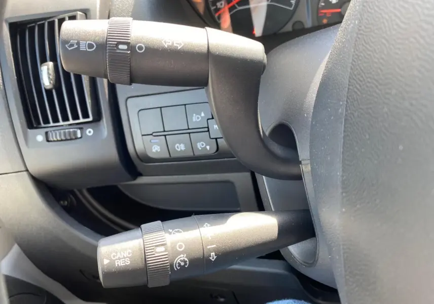 Gros plan sur les commandes au volant du Citroën Jumper 2023, avec régulateur de vitesse et leviers noirs.