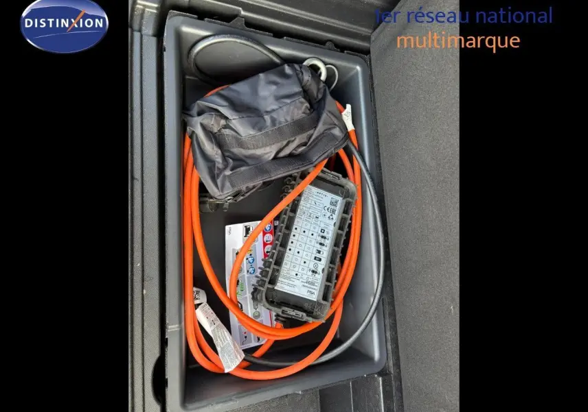 Vue plongeante sur le coffre d'un Peugeot 3008 gris platinium, montrant le câble de recharge hybride rangé.