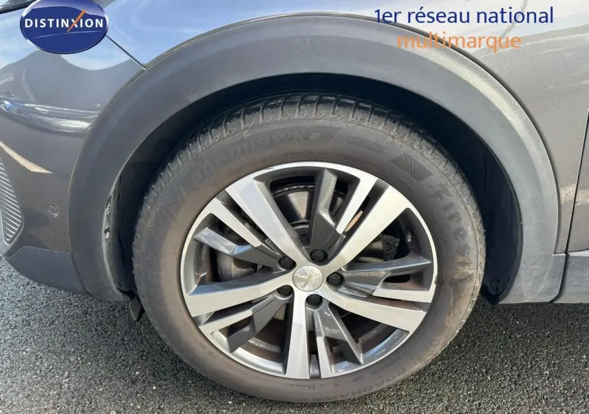 Gros plan sur la roue avant gauche du Peugeot 3008 gris platinium, mettant en valeur la jante alliage et le pneu Firestone.