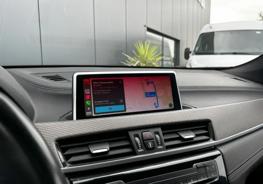 Tableau de bord de BMW X2 F39 2021 avec écran GPS tactile affichant un itinéraire, ambiance intérieure moderne.