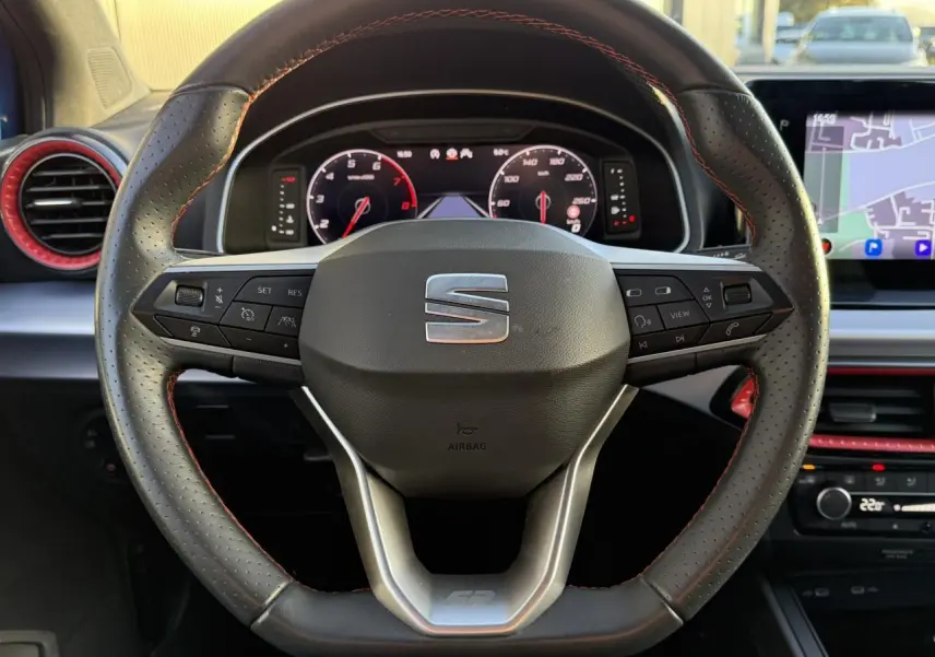 Volant en cuir perforé avec surpiqûres rouges et tableau de bord digital d'une SEAT Ibiza TSI 115 FR 2025.