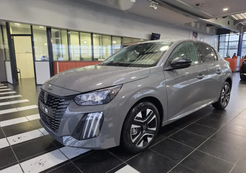 Peugeot 208 gris selenium en 3/4 avant droit, avec calandre noire et jantes alliage bi-ton.