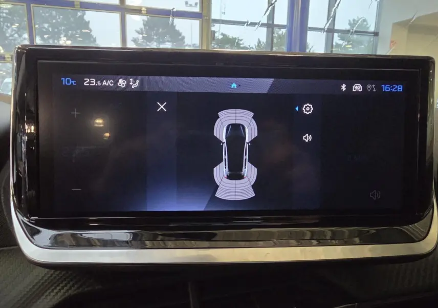 Écran tactile central du Peugeot 208 2025 affichant l'aide au stationnement avec vue de dessus du véhicule.