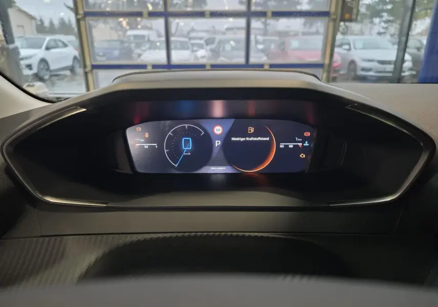 Tableau de bord numérique de Peugeot 208 hybride, affichage digital clair avec indicateurs de vitesse et alertes.