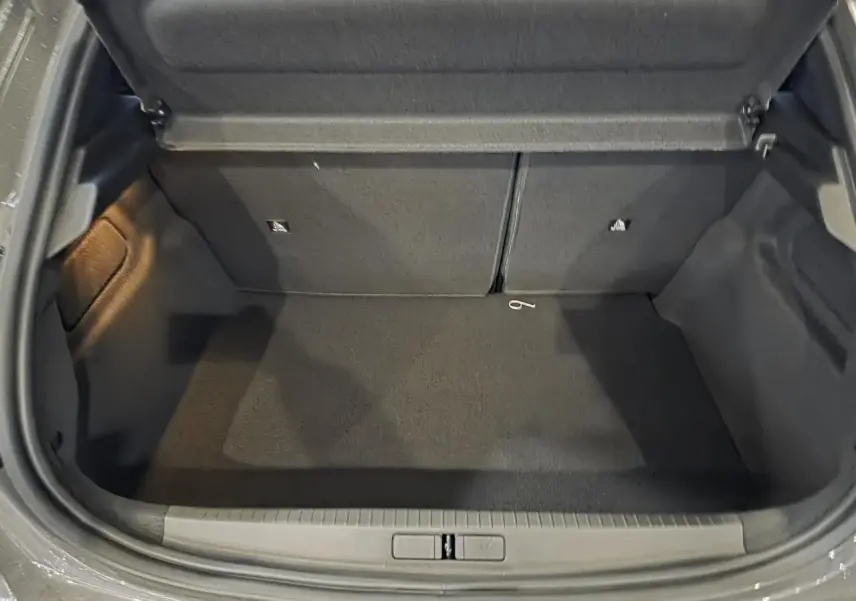 Coffre ouvert de Peugeot 208 gris Selenium, montrant l'espace de chargement vide et la moquette noire.