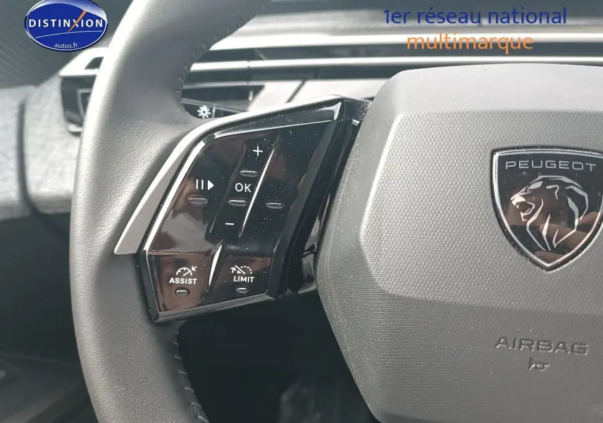 Gros plan sur le volant cuir multifonction gris avec logo Peugeot et commandes intégrées à gauche, intérieur du 5008 2025.