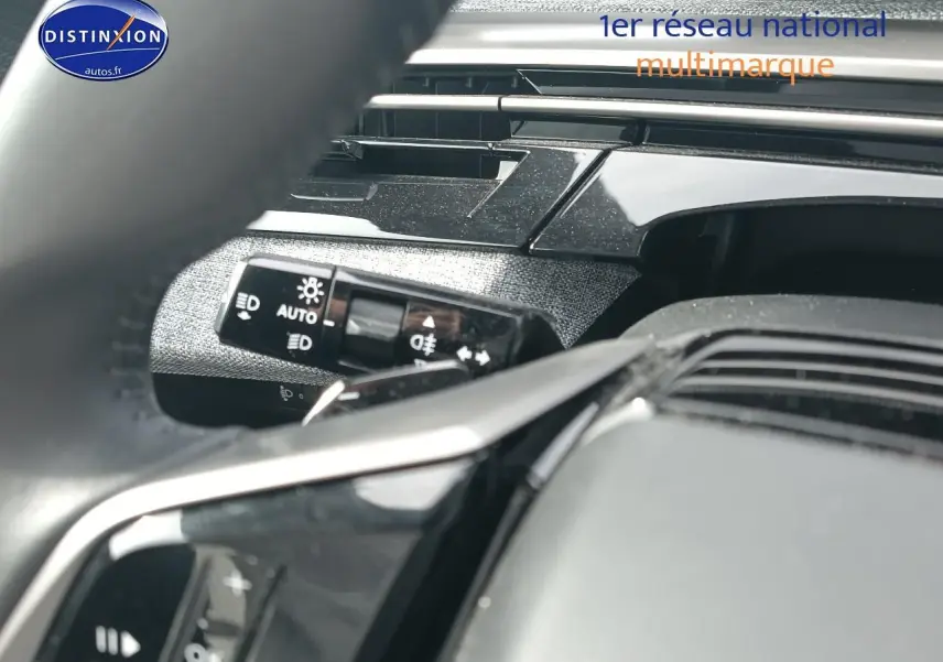 Gros plan sur la commande des phares et partie du volant cuir noir du Peugeot 5008 Hybrid 145 allure 2025.