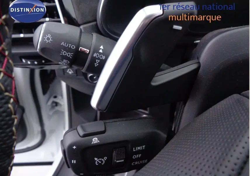 Gros plan sur les commandes au volant du DS7 Crossback blanc nacré, mettant en valeur les réglages du régulateur de vitesse.